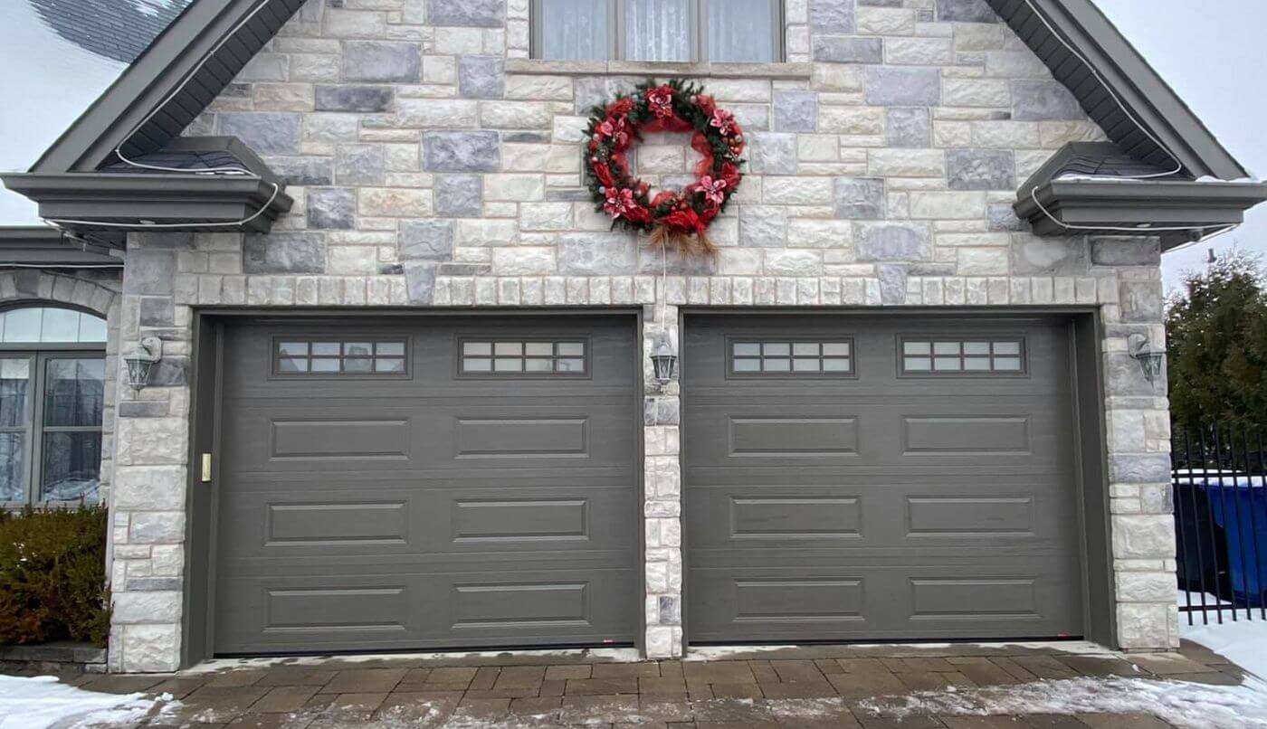 Deux portes de garage grises avec des fenêtres pour laisser entrer la lumière.