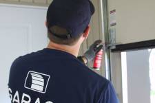 Un technicien certifié en train de lubrifier les roulettes d'une porte de garage